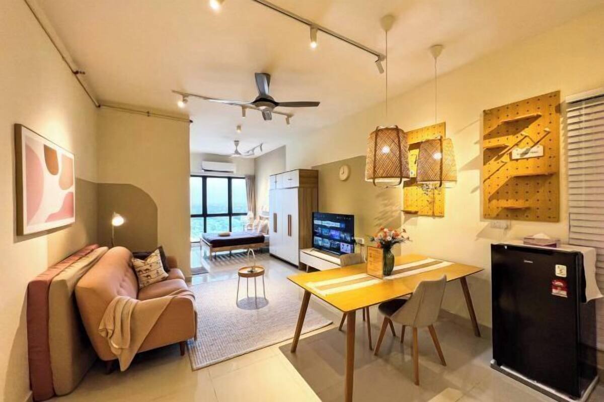 A modern living room with a sofa, a dining table, and a TV. There is a ceiling fan and a wall-mounted shelf with decorative items.