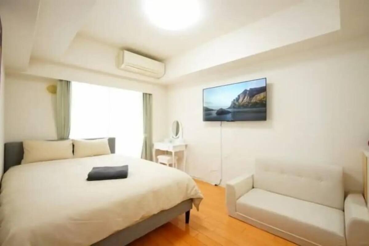Hotellihuoneessa on sänky, sohva, työpöytä ja seinälle asennettu televisio.