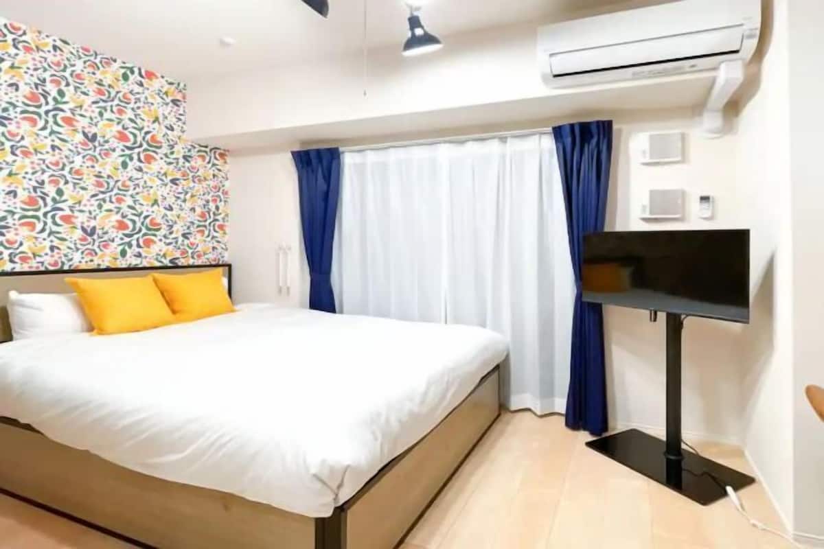 A bedroom with a bed, a TV, and an air conditioner.