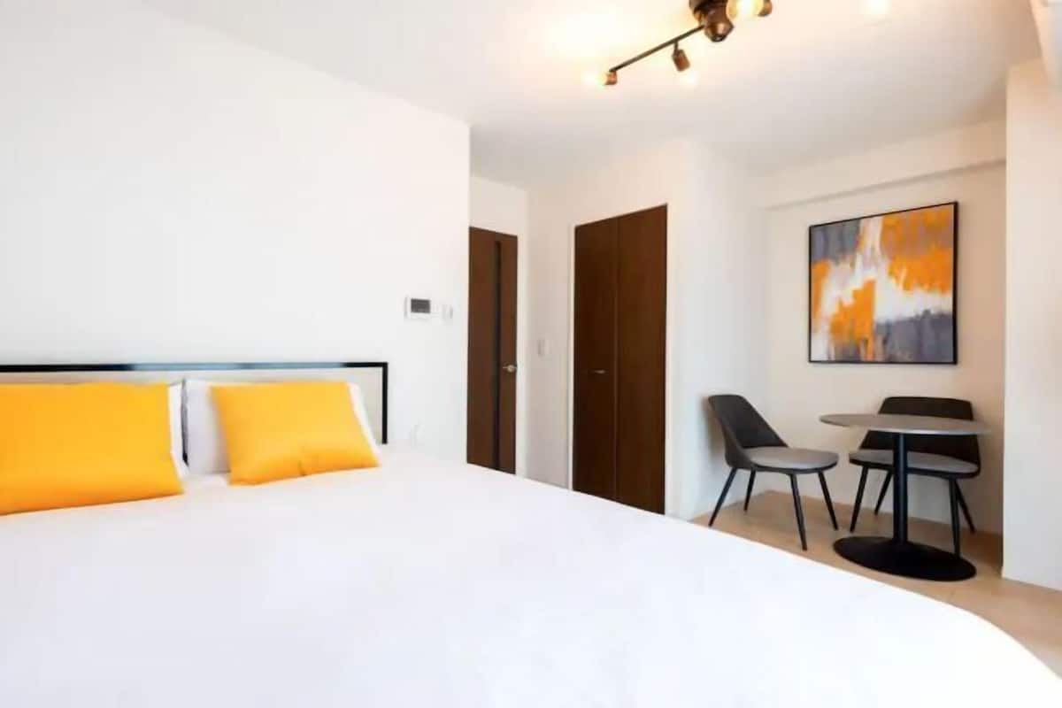 A modern hotel room with a large bed, a desk with two chairs, and a painting on the wall.