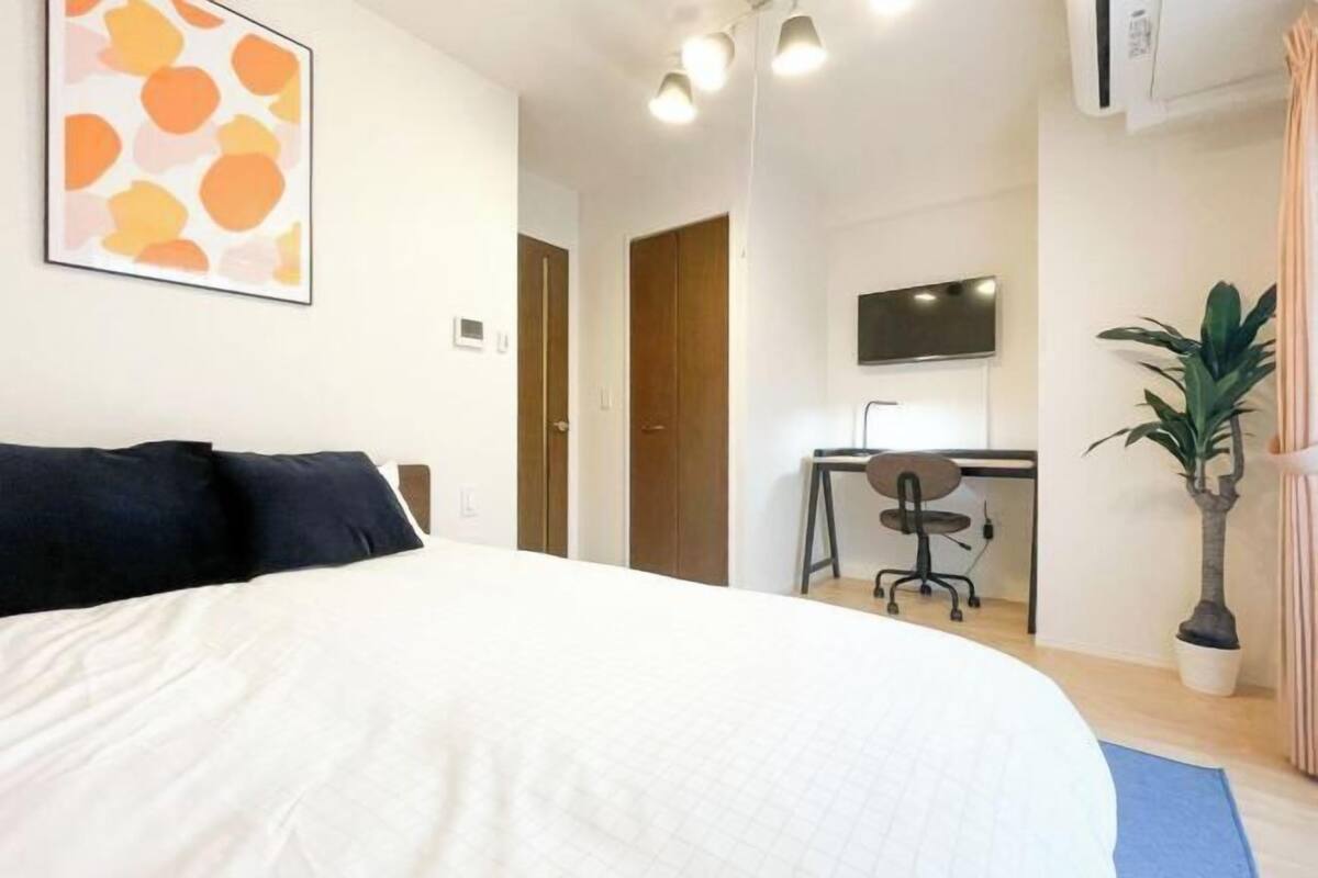 A bedroom with a large bed, a desk, a chair, and a television.