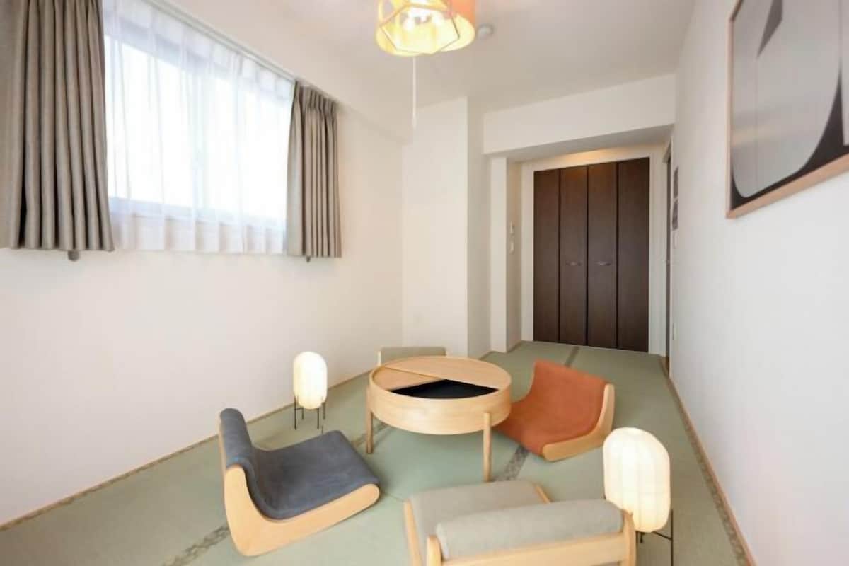 A room with a low ceiling, a round table with chairs, a sofa, and a bed.