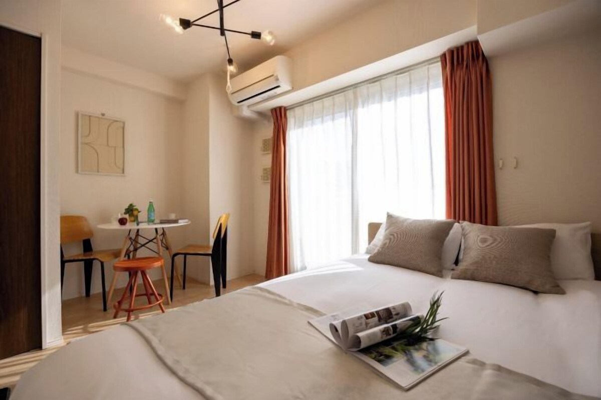 A hotel room with a bed, a small table, and a chair.
