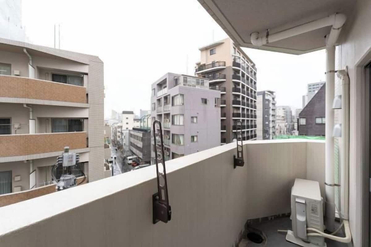 A balcony with a view of surrounding buildings, a small outdoor utility area, and a window with a view of the cityscape.