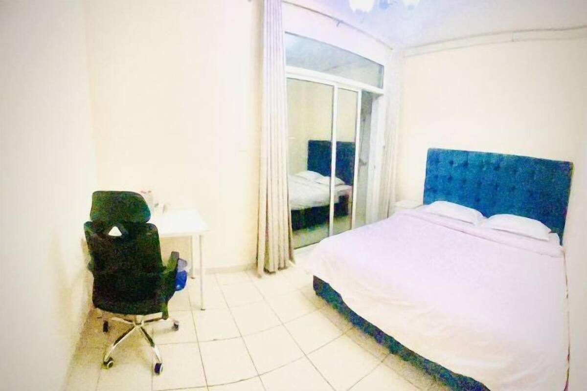 Une chambre à coucher comprenant un lit, une chaise, une petite table et une porte-fenêtre coulissante.