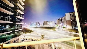 Un paisaje urbano nocturno con edificios modernos y una avenida amplia.