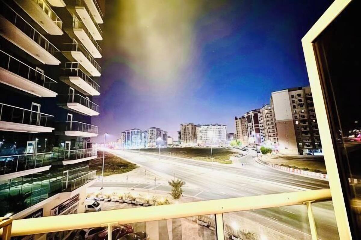 Une vue nocturne d’une ville avec des bâtiments modernes et une large avenue.