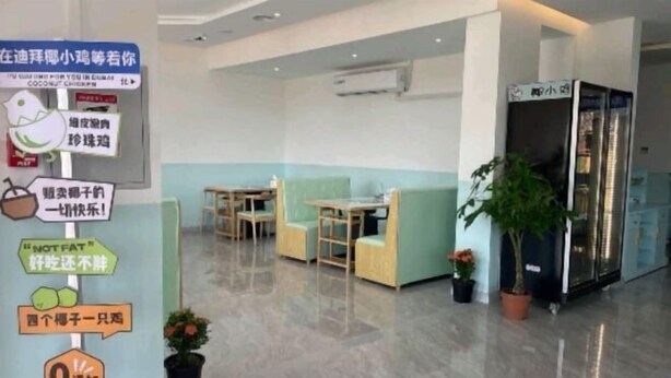 Un moderno vestíbulo de hotel con mostrador de recepción, zona de estar y un refrigerador.