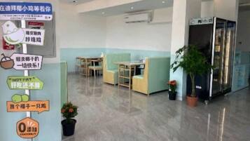 A modern hotel lobby with a reception desk, seating area, and a refrigerator.