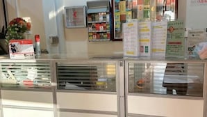 Zona de recepción con mostrador, vitrinas de vidrio y varios carteles informativos.