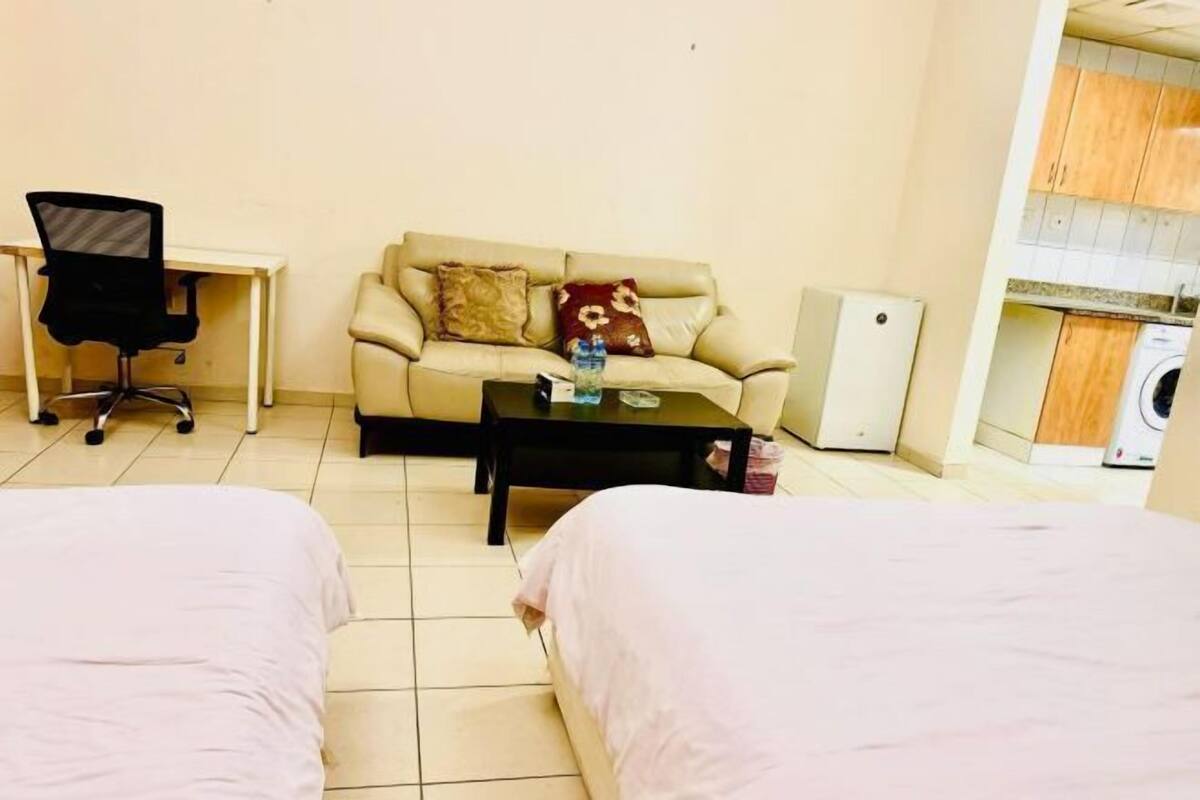 Une chambre d’hôtel avec deux lits, un canapé, un bureau et une petite kitchenette.