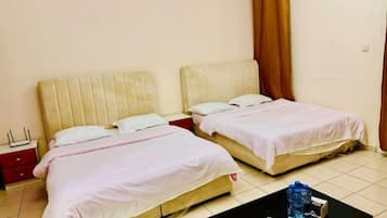 A hotel room with two beds, a small table with a water bottle, and a nightstand with a lamp.