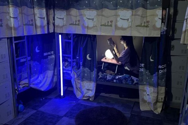 A room with a bed, a desk, and a chair. There is a curtain with a bear design.