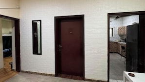 A room with white brick walls, a wooden door, and a small window. - Orange Home Vacation (Dubai)