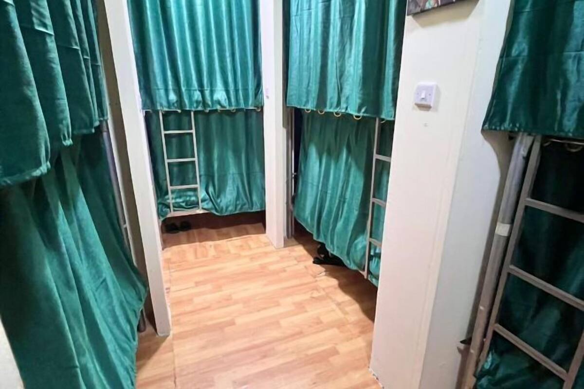 A narrow hallway with wooden flooring and green curtains.