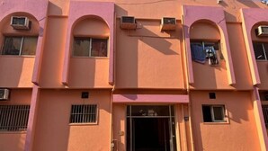 A pink building with multiple windows, air conditioning units, and a visible entrance. - Orange Home Vacation (Dubai)