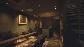 A modern living room with a sofa, coffee table, and chairs. There is a painting on the wall and a staircase in the background. - At Hotel ORTO (Fukuoka)