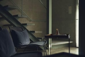 A modern interior with a staircase, a chair, and a table with a book. - At Hotel ORTO (Fukuoka)