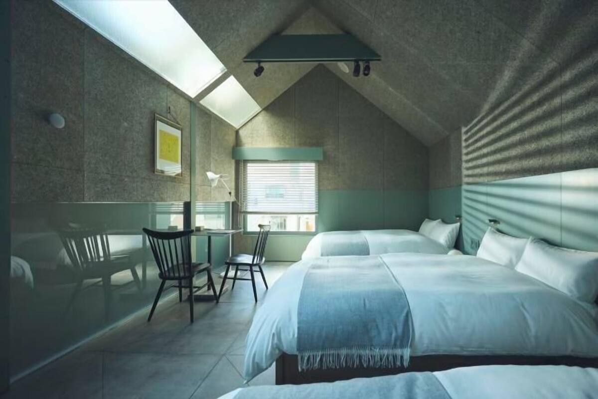 A bedroom with two beds, a desk, and a chair.