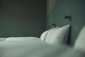 A bed with white bedding in a room with a textured wall and a small, dark object on the wall. - At Hotel ORTO (Fukuoka)