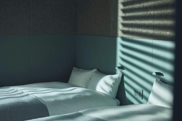 A hotel room with a bed, pillows, and a wall with a textured pattern.