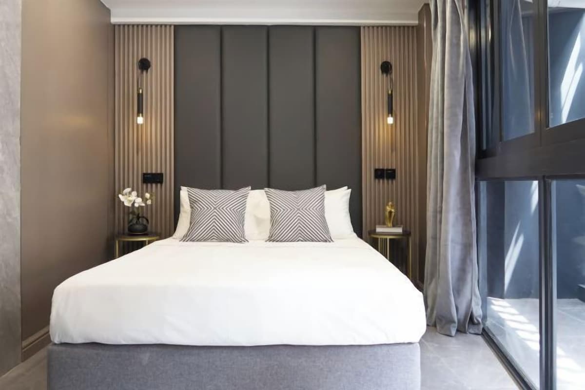 Ein modernes Hotelzimmer mit einem großen Bett, zwei Nachttischen und einem großen Fenster.