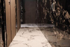 Un pasillo con suelo de mármol y una puerta de madera a la izquierda.