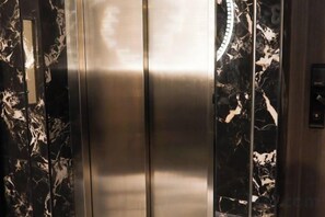 Un ascensor con detalles metálicos y diseños que imitan el mármol en las paredes.