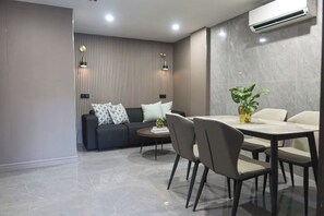 Una sala de estar moderna con un sofá, una mesa de comedor con sillas y una planta en maceta.