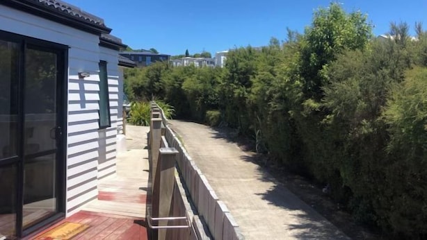 Una propiedad residencial con un área de patio, cerca de madera y abundante vegetación.