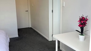 Una habitación de hotel con una cama, una pequeña mesa blanca y una planta en maceta.