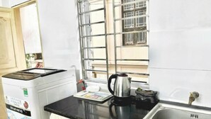 A kitchen with a washing machine, a kettle, and a sink. - Hoe Stay - Where to stay (Hanoi)