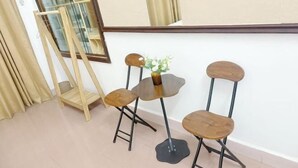 A room with a small round table, two wooden chairs, a mirror, and a window with curtains. - Hoe Stay - Where to stay (Hanoi)