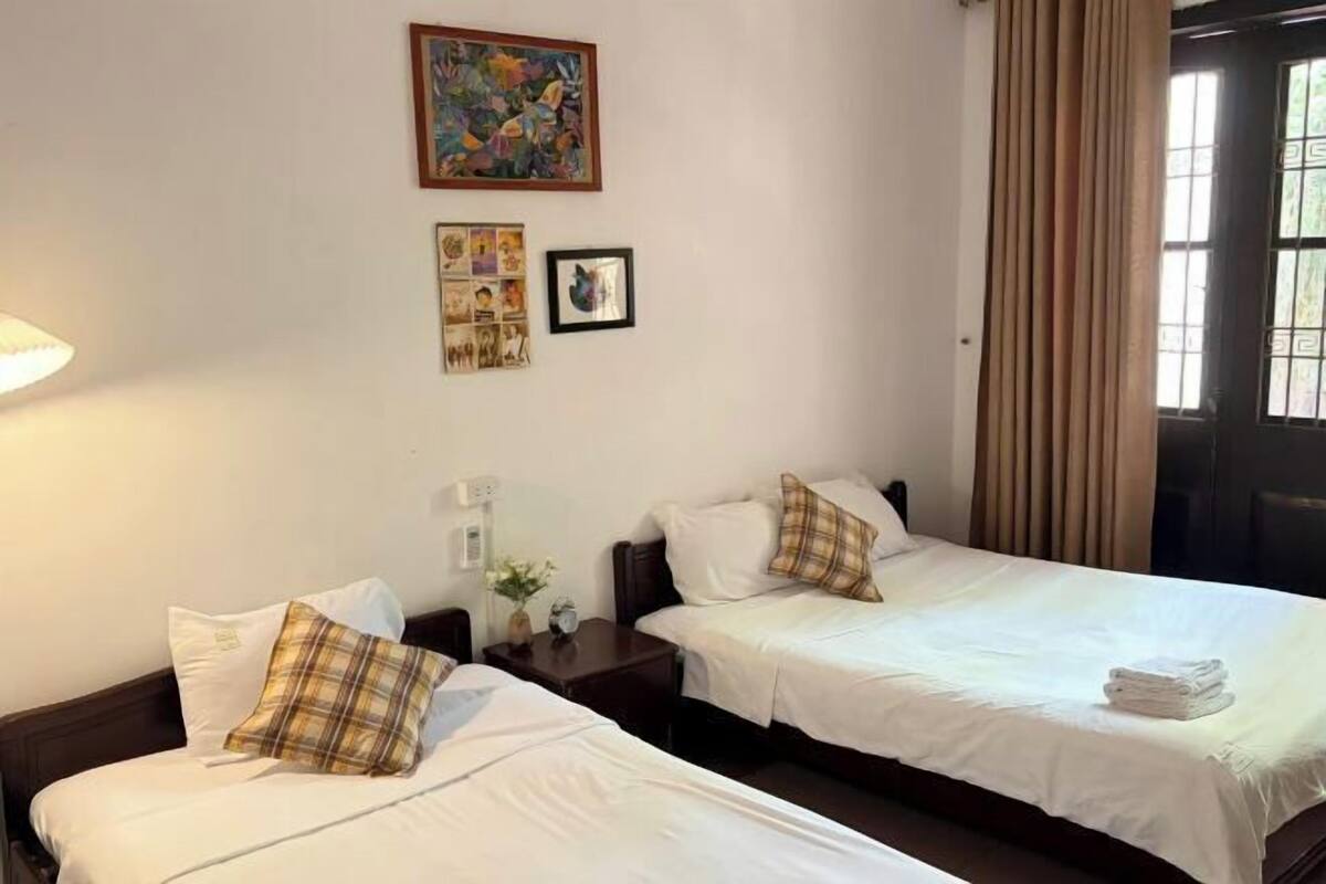 Une chambre d’hôtel avec deux lits, une table de chevet, une lampe et un tableau au mur.