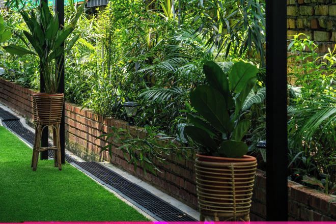 Un jardín exuberante con un muro de ladrillo, césped verde y diversas plantas.