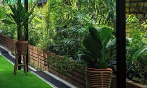 Un jardín exuberante con un muro de ladrillo, césped verde y diversas plantas.