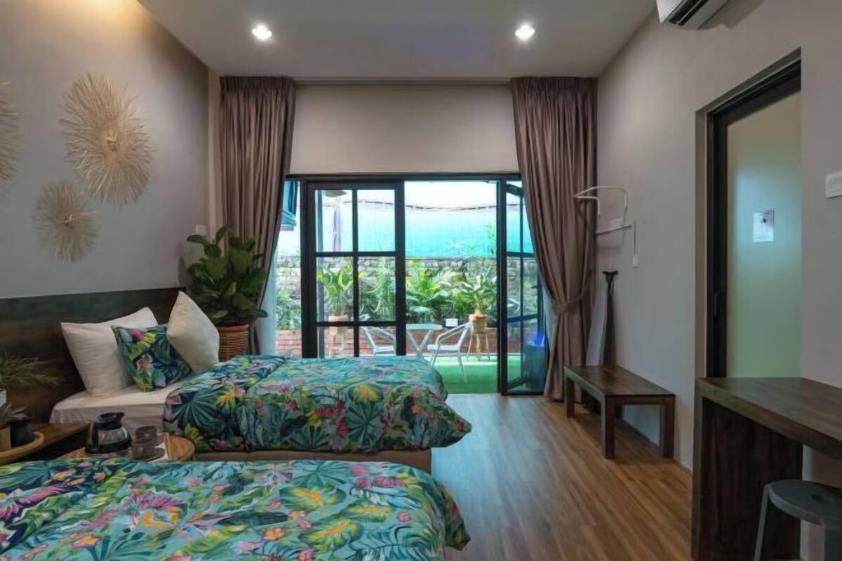 Un dormitorio con dos camas, un escritorio, una silla y vistas al exterior.