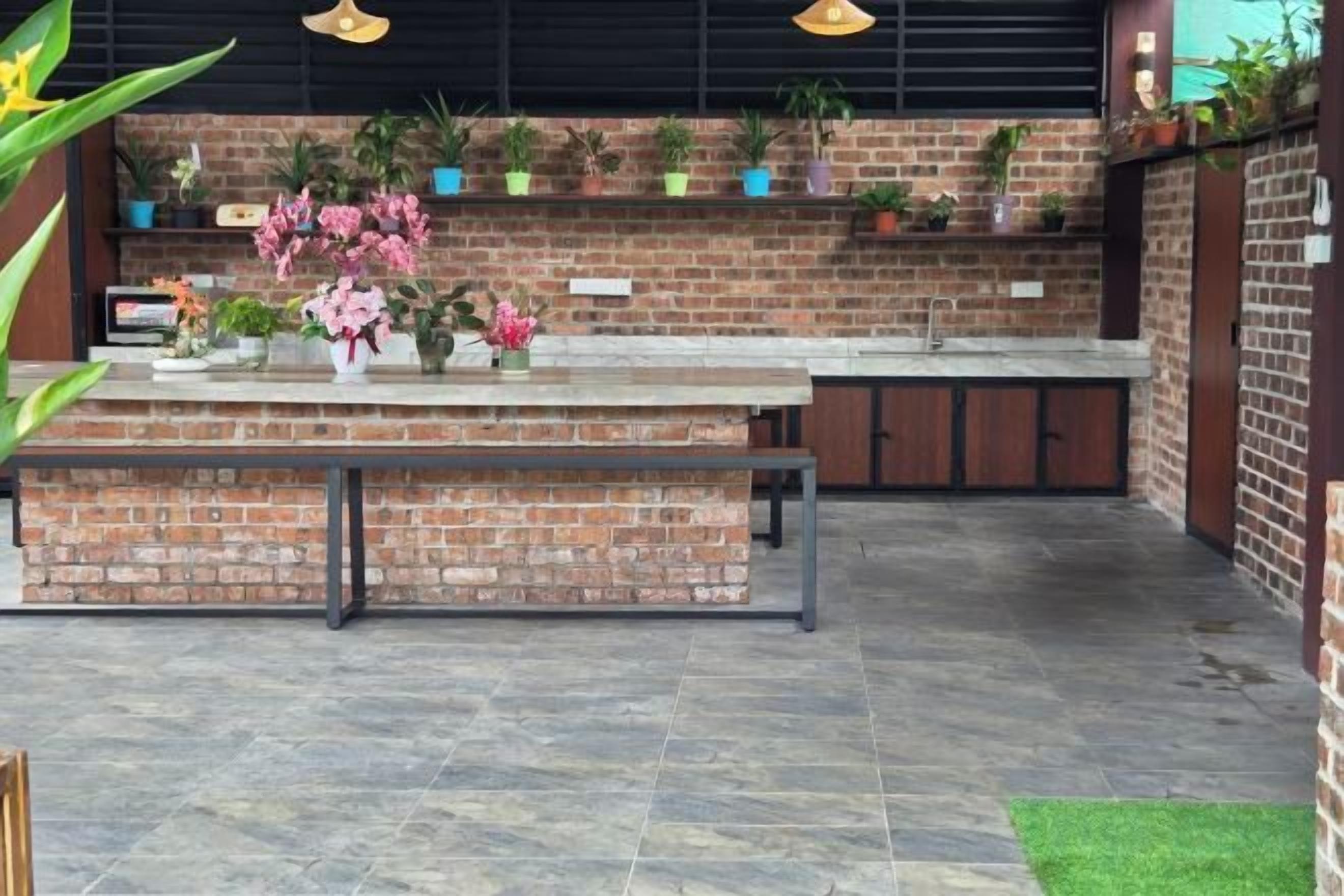 A brick kitchen area with a counter, bench, and potted plants.