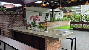 An outdoor bar area with a concrete countertop, a bench, and potted plants.