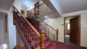 Un escalier avec des rampes en bois et des marches recouvertes d’une moquette rouge.