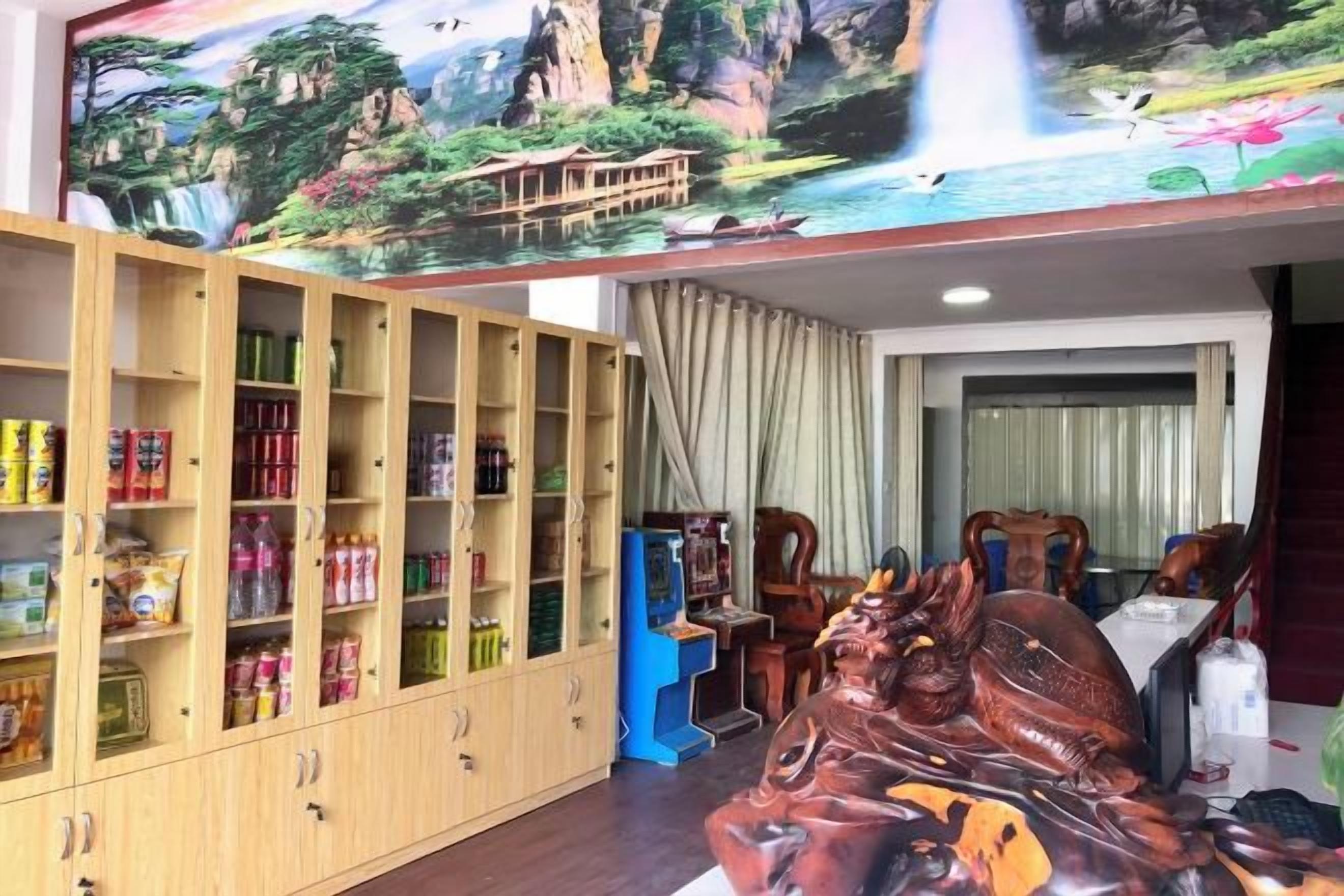 A room with a wooden cabinet filled with snacks, a blue arcade machine, and a large wooden horse sculpture.