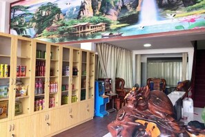 Une pièce comprenant un buffet en bois rempli d’en-cas, une borne d’arcade bleue et une grande sculpture équestre en bois.