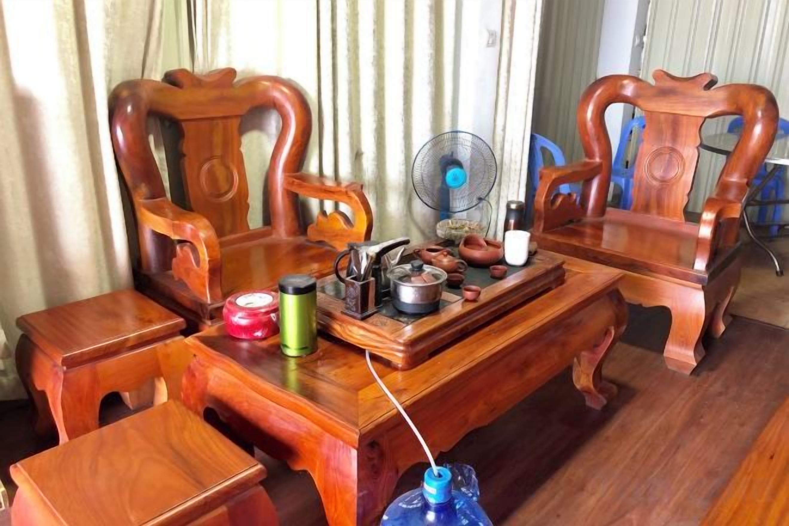 A wooden dining table with chairs, a fan, and various kitchen items.