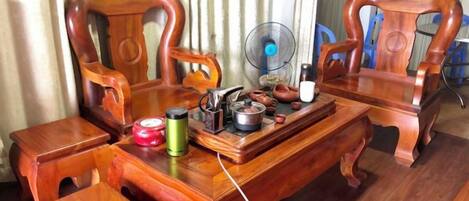 A wooden dining table with chairs, a fan, and various kitchen items.