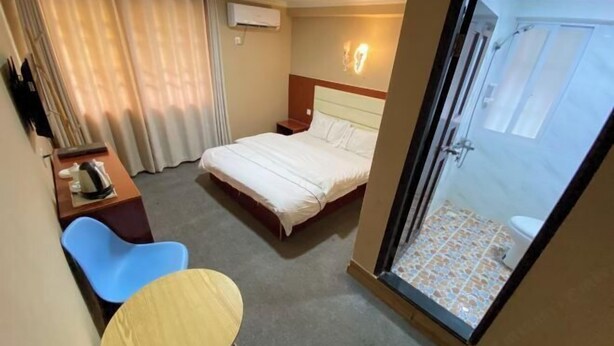 Une chambre d’hôtel comprenant un lit, un bureau, une chaise, une petite table et un espace douche.