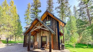 Une cabane rustique dotée d’un porche, d’une façade en bois et d’une allée gravillonnée.
