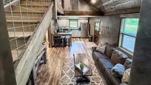 Un vaste espace de vie de style loft, doté d’un haut plafond, d’un escalier, d’une cuisine et d’un coin salon avec un canapé et une table basse.