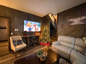 A living room with a television, a Christmas tree, a sofa, and a coffee table.