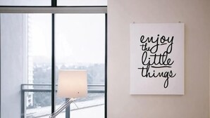 Une pièce avec une grande fenêtre, une lampe et une citation inspirante sur le mur.