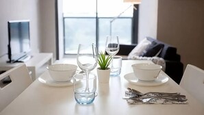Une table à manger avec de l’assiette, des bols et des verres blancs, une petite plante en pot et un menu.